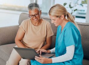 Older adult and family member reviewing care options at a kitchen table with documents and a notebook.